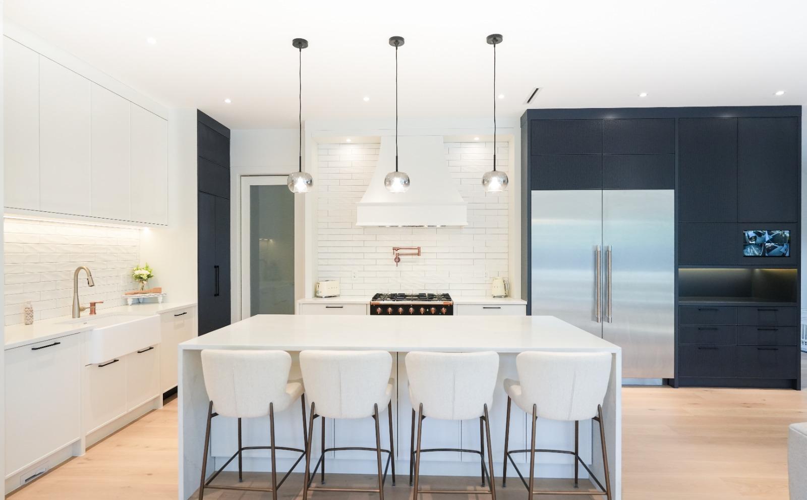 A white kitchen island with five stools under three glass pendants.